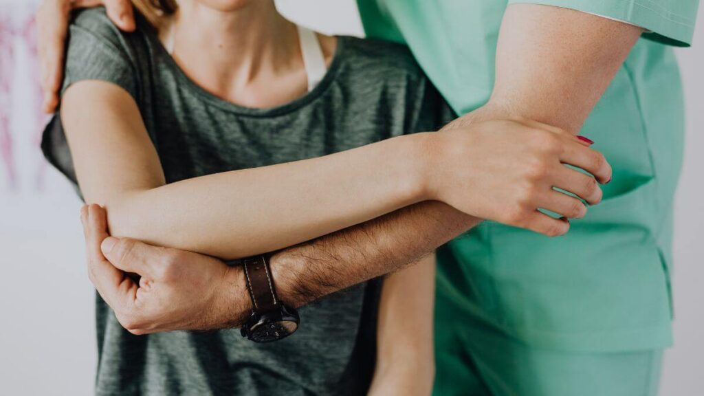 A healthcare professional is assisting a patient by holding and guiding their arm.