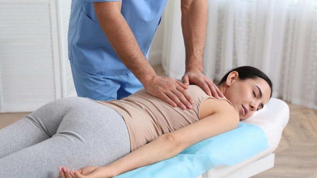 A person receiving a massage, with a practitioner applying pressure to their back.